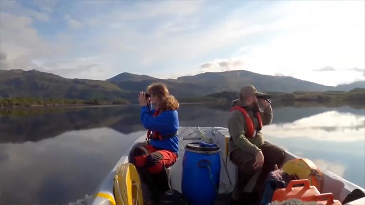 Two people on a boat facing opposite directions and looking through binoculars.