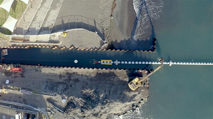 A canal splitting two pieces of land under construction, with a vessel going through it. 