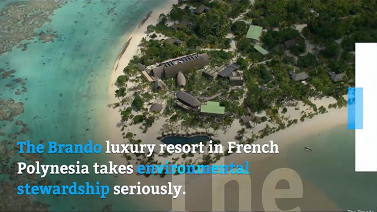 A compound with different buildings surrounded by greenery and set along the coast with light blue water and blue and white text overlaying the image.