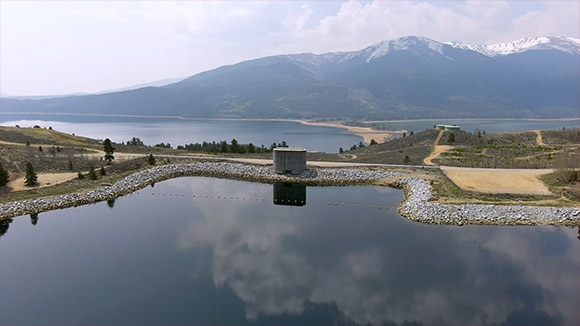 A narrow piece of land separates two bodies of water reflecting the sky with a mountain in the background