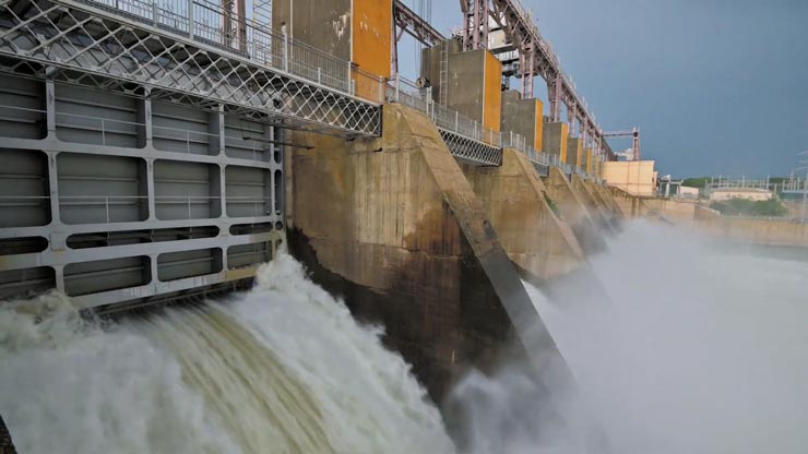 A turquoise lake in the forefront and brown mountains in the background with scattered wind turbines and white text across the image