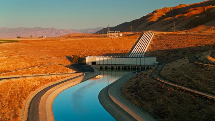 A puddle with a stick in the middle, and debris and a car blurry in the background