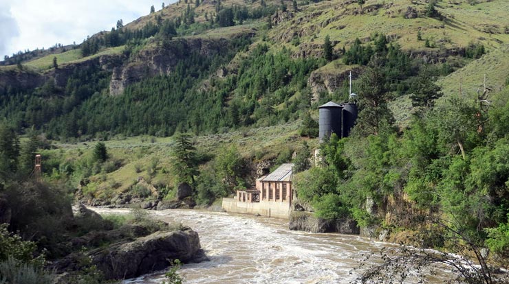 A building tucked into a green mountainside along a river