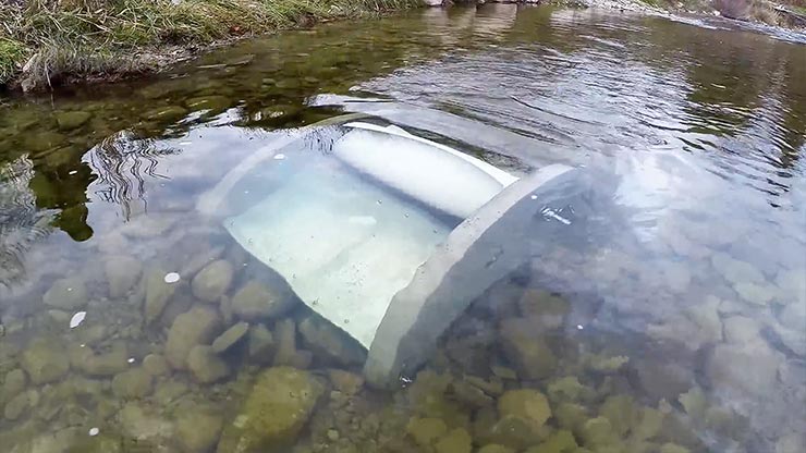 A silver marine energy device glistening under the surface of a river.