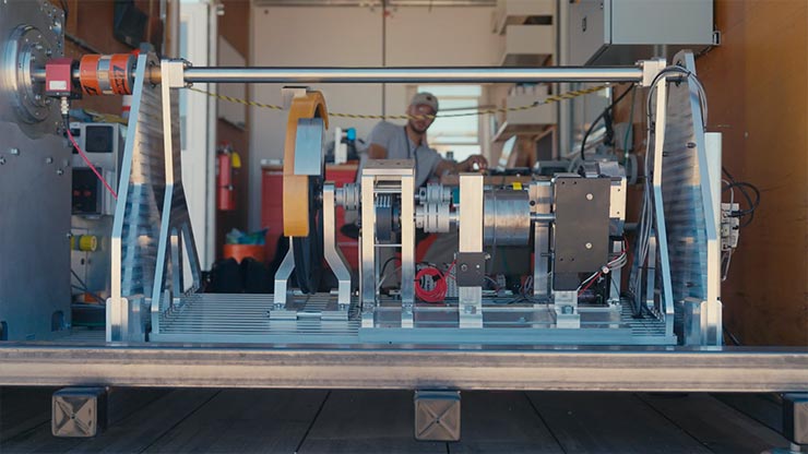 A person testing a wave energy converter, which is at the forefront to showcase the details of the device. 