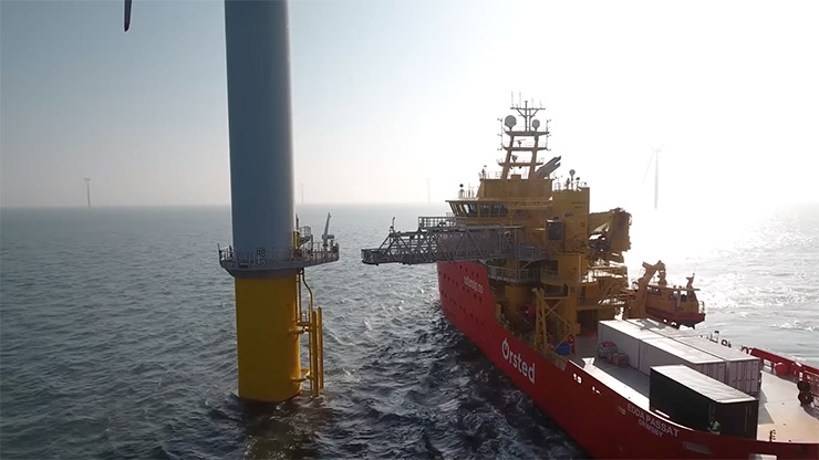A large barge near a floating yellow platform with a white tower attached.