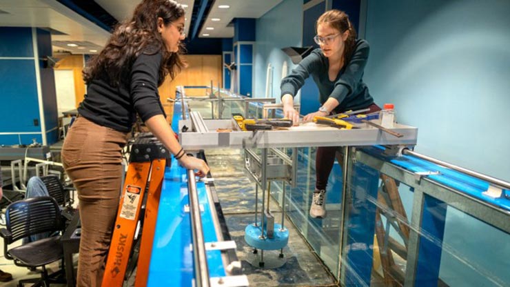 Two people interacting with a marine energy device in a wave tank.