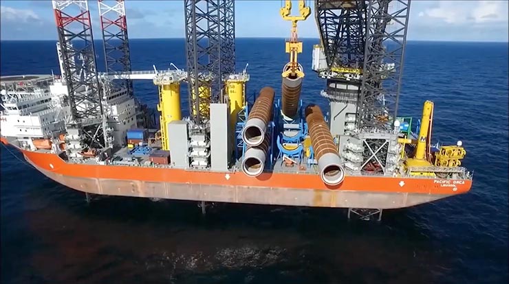 A cargo ship in the ocean carrying various industrial materials and cranes.